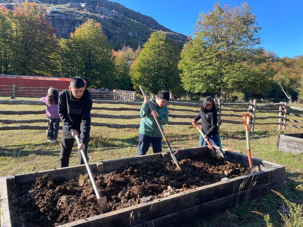 Tres estudiantes preparan una huerta con palas en Parque Escuela Kaikén