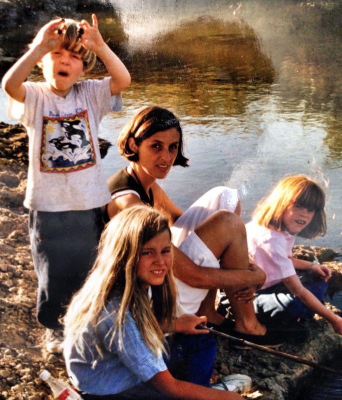 Una madre y tres niños junto a un río, en una salida familiar