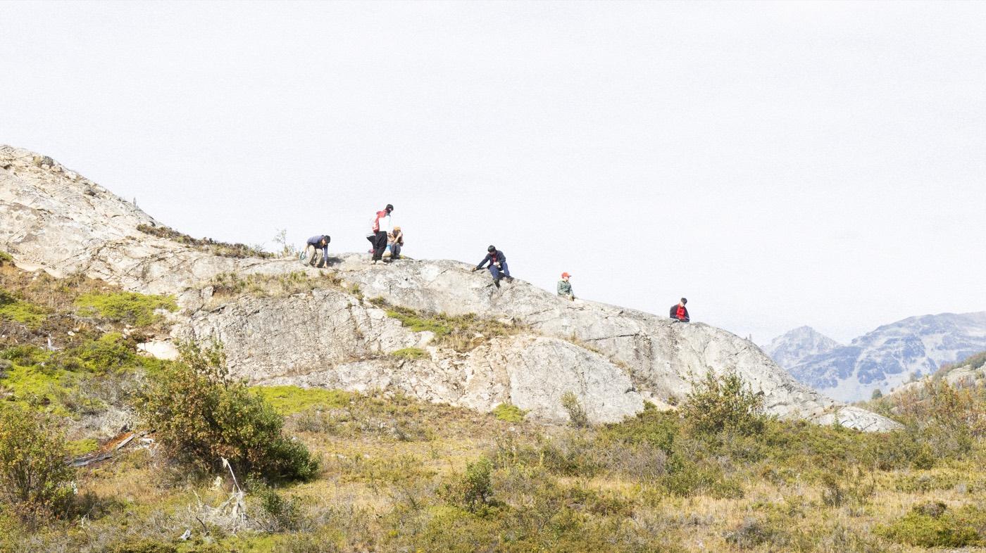 Estudiantes caminan por un sendero de piedra con las montañas nevadas al fondo