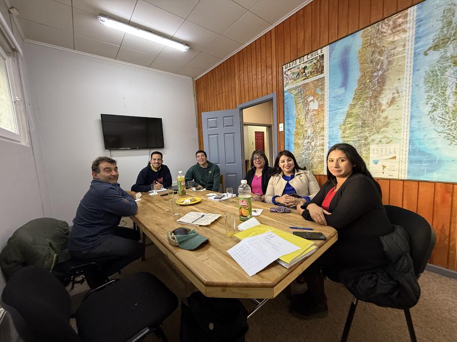 Equipo directivo y docente reunido en torno a una mesa, con un mapa de Chile en la pared