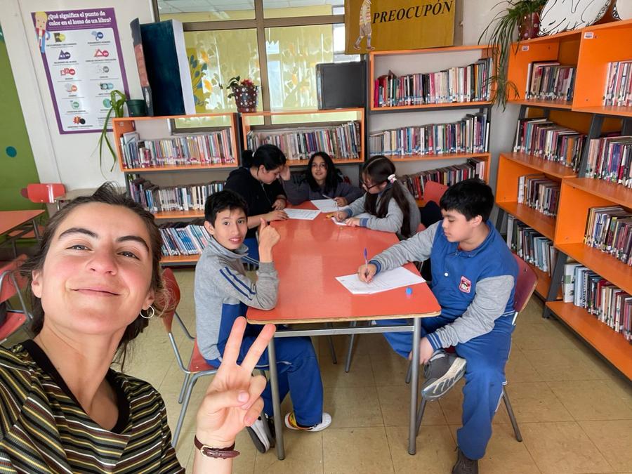 Estudiantes responden un cuestionario en la biblioteca junto a una educadora