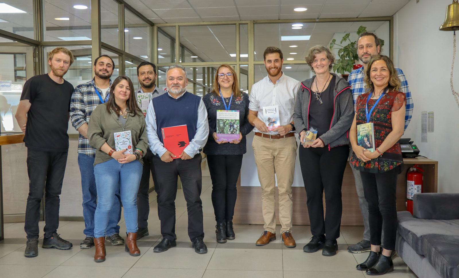 Un grupo de adultos posa con libros y materiales pedagógicos en el hall de un establecimiento
