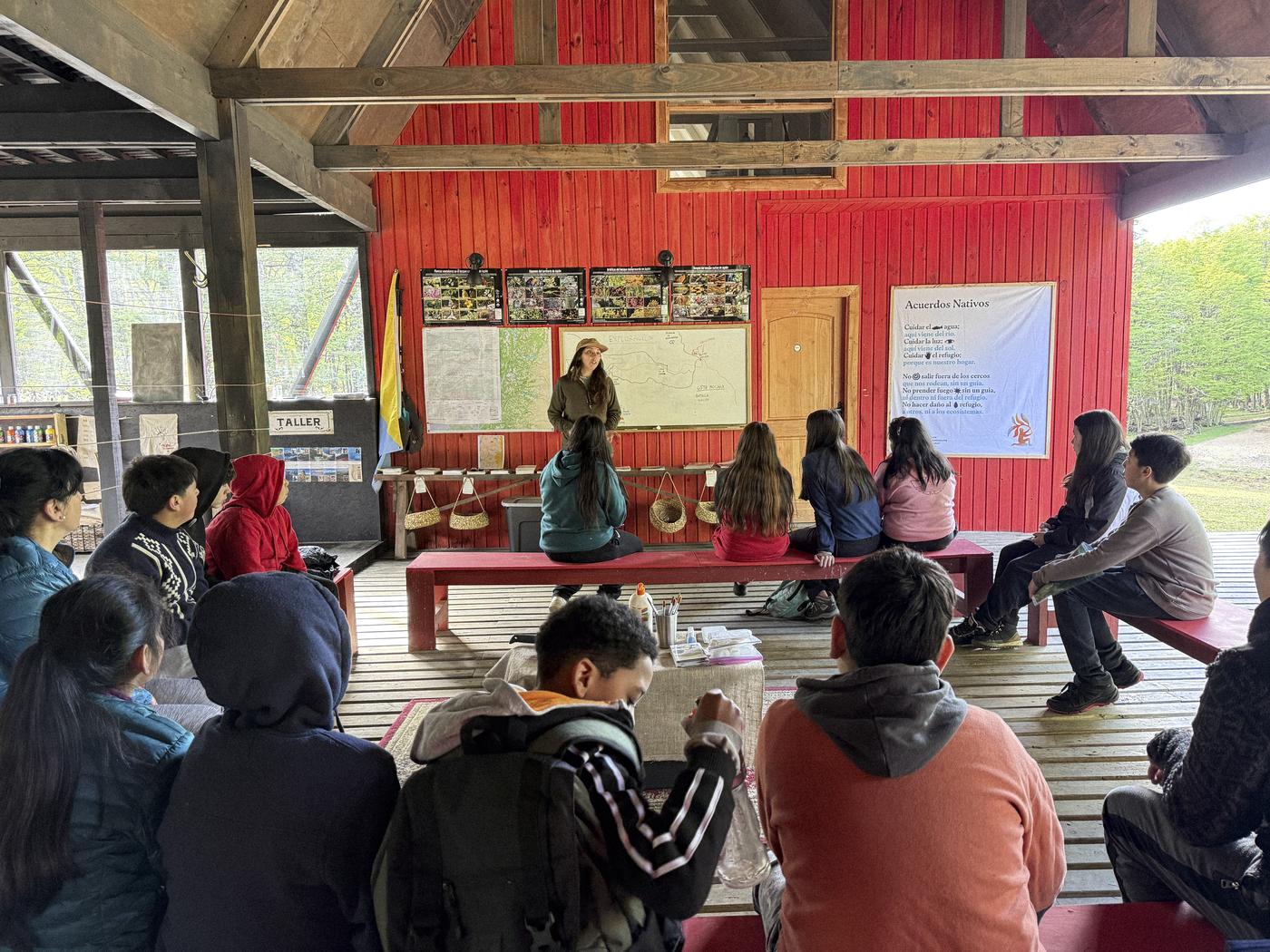 Estudiantes sentados en la galería roja del refugio durante una presentación