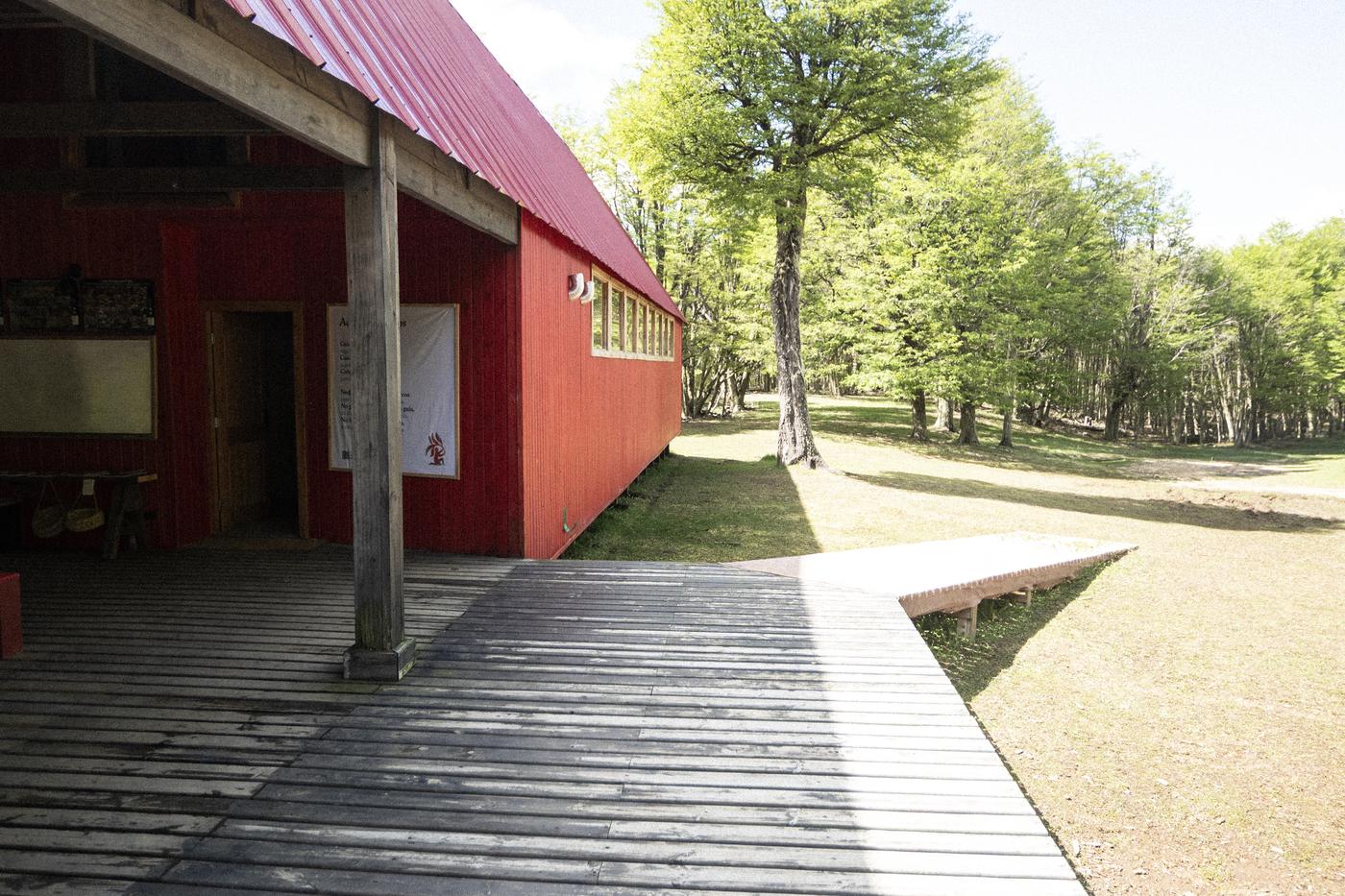 La galería roja del Refugio Escuela de Kaikén y su pasarela de madera hacia el bosque