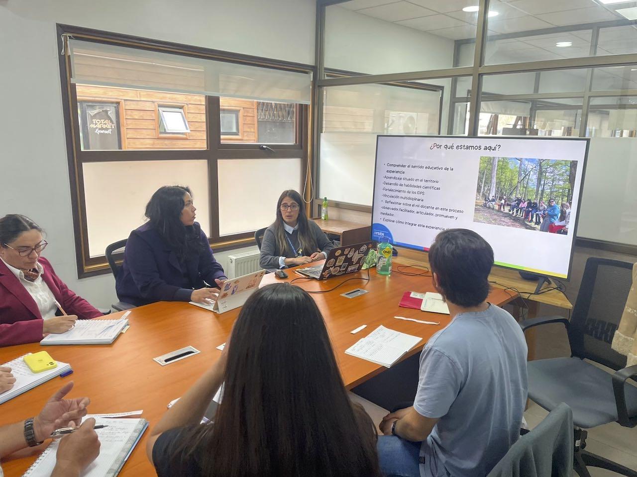 Docentes y equipo de Nativos reunidos alrededor de una mesa, con una presentación en pantalla, diseñando el plan